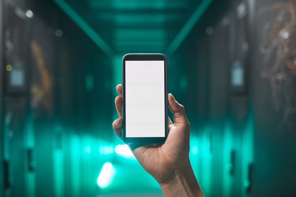 Close up of male hand holding smartphone with blank white screen in futuristic server room, copy space